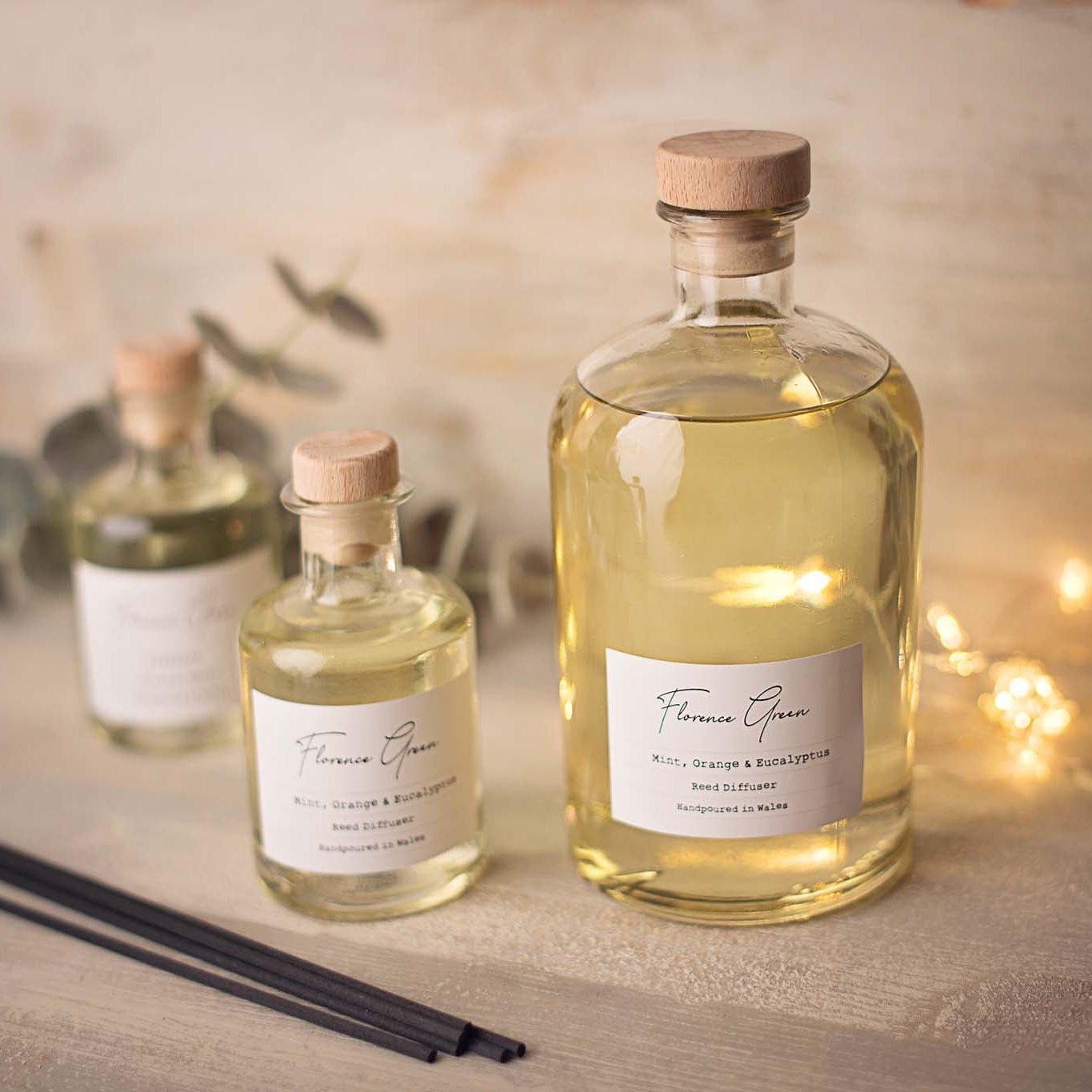 Three bottles of Florence Green essential oils on a wooden surface with a warm glow.