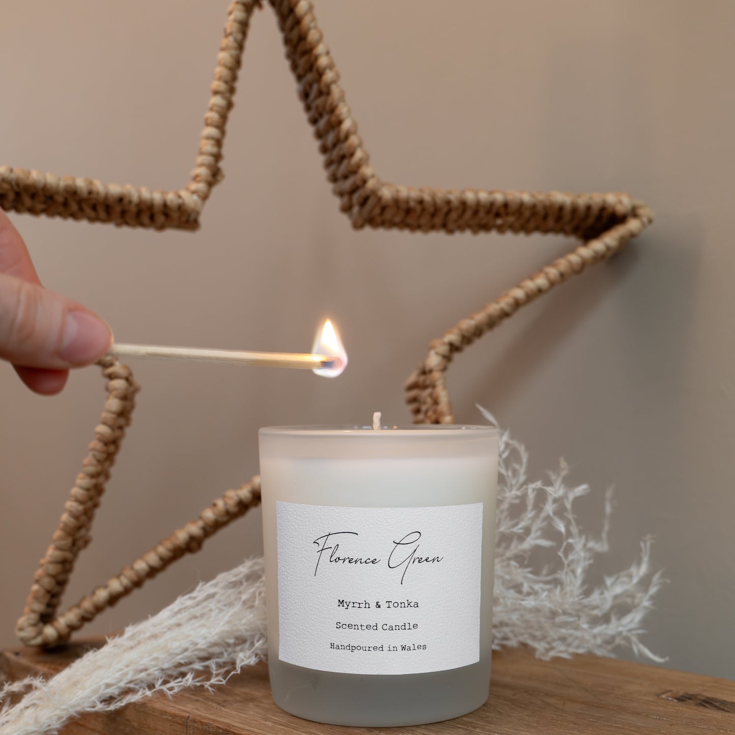 Candle being lit with a match on a wooden stool against a star-shaped decoration.