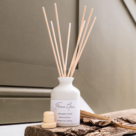 Diffuser with wooden sticks on a wooden platform against a neutral background