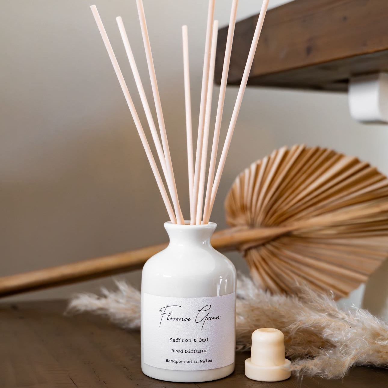 White diffuser bottle with wooden sticks on a wooden surface
