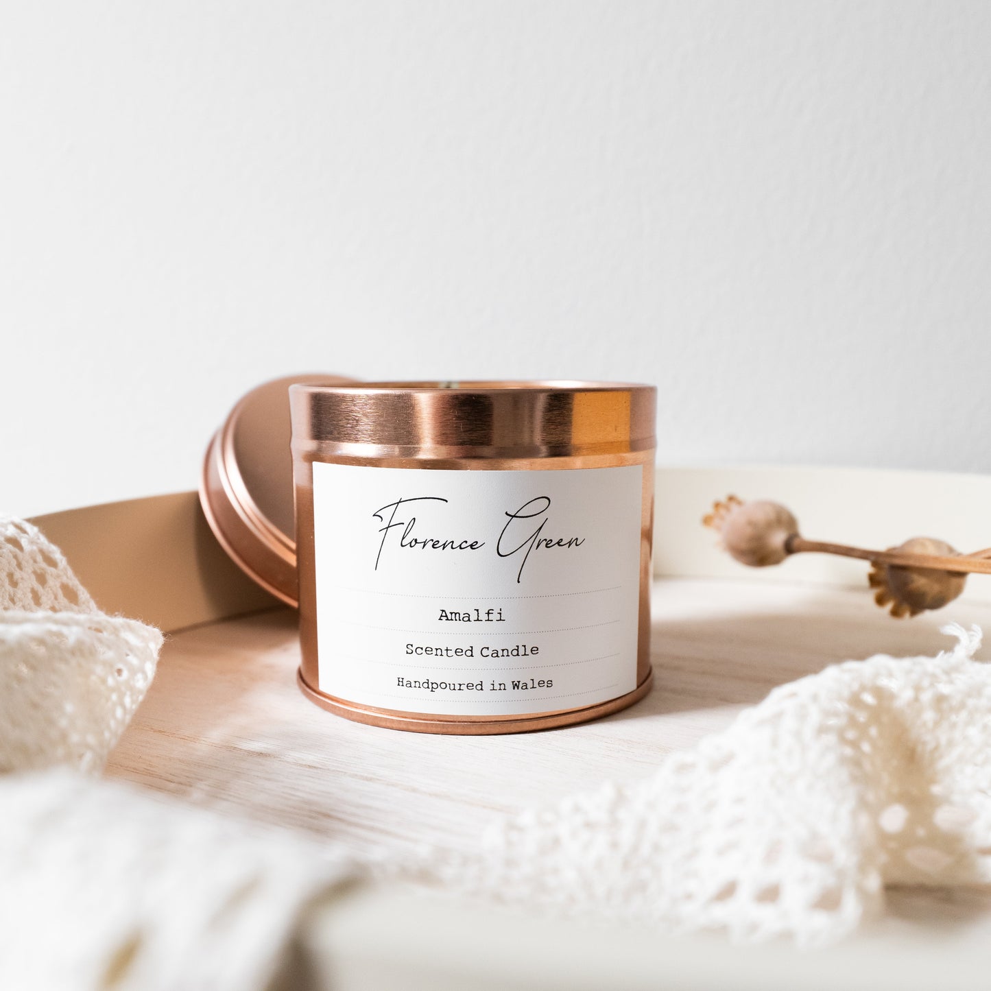Candle with a copper lid on a white surface with decorative elements