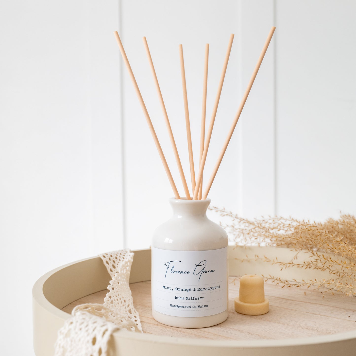 White diffuser bottle with wooden sticks on a wooden tray with a white background