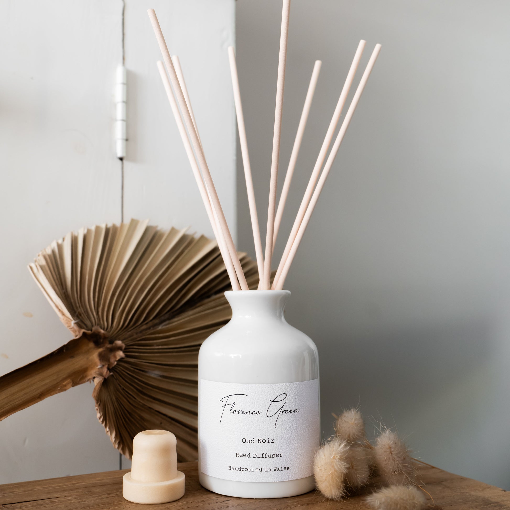 White diffuser bottle with wooden sticks on a wooden surface with a neutral background