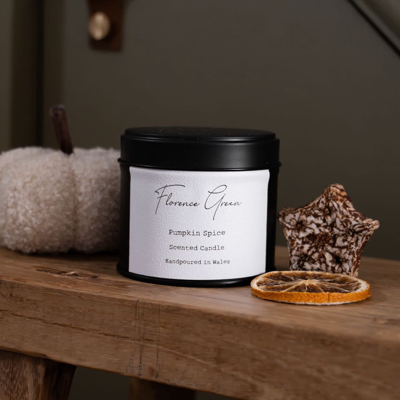 Candle with a label on a wooden surface with decorative items