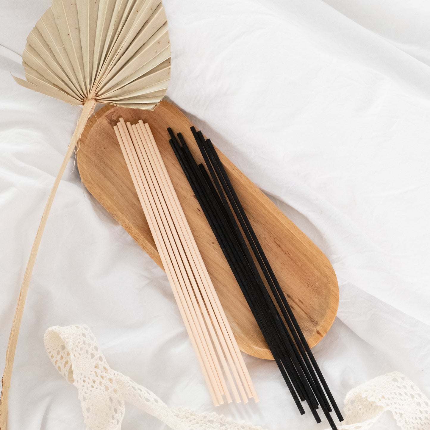 Wooden incense holder with beige and black sticks on a white fabric background