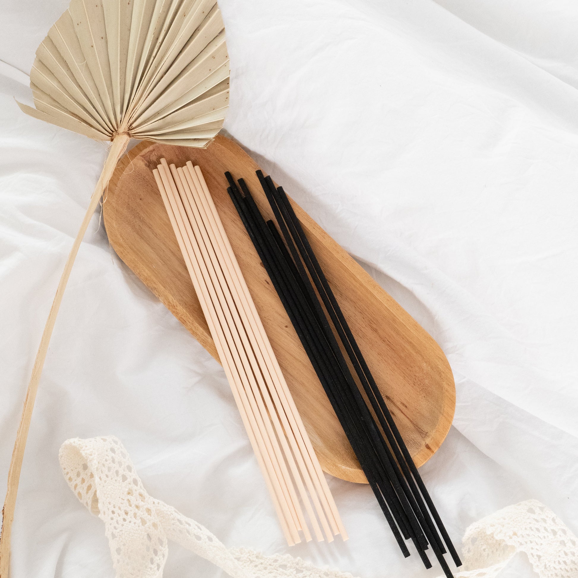 Wooden incense holder with beige and black sticks on a white fabric background