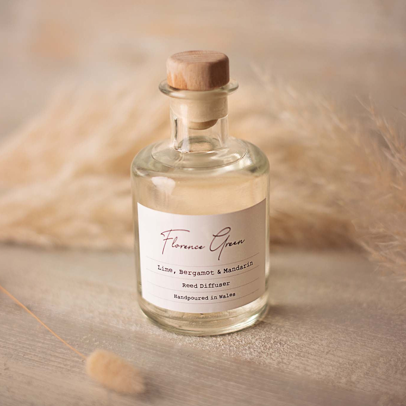 Glass bottle with cork lid on a wooden surface with dried plants