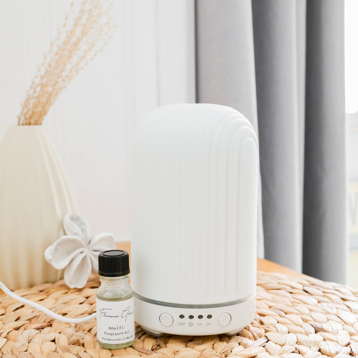 White diffuser on a woven surface with a small bottle of essential oil next to it, against a neutral background.