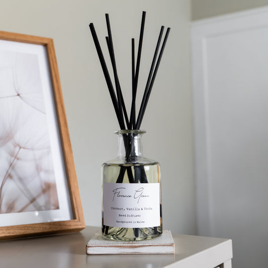 Diffuser with black sticks on a white surface next to a framed picture.
