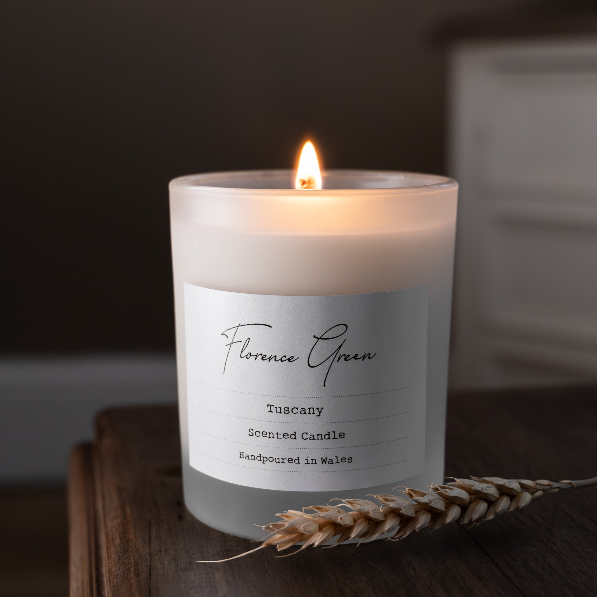 Candle with a label on a wooden surface, blurred background