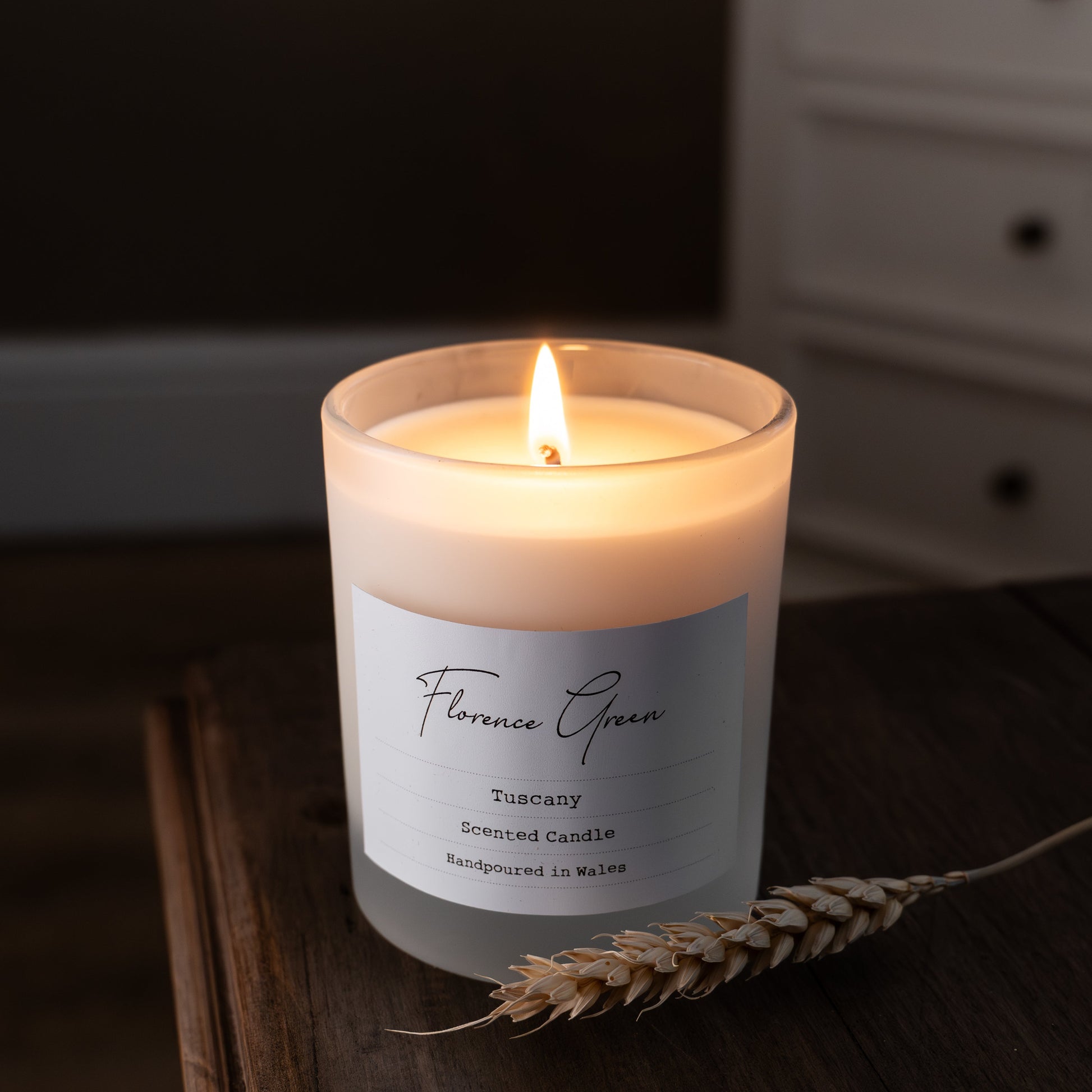 Candle with a label on a wooden surface, with a blurred background