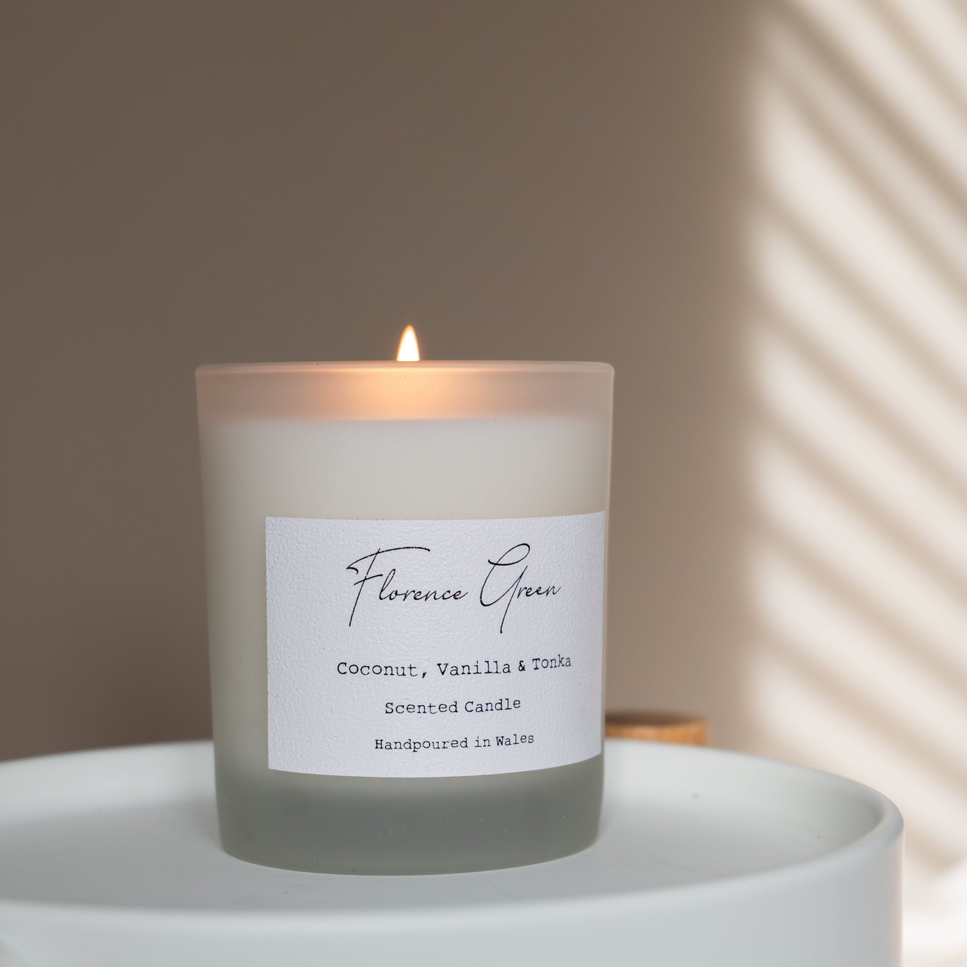 Candle with a label on a small round table with a neutral background
